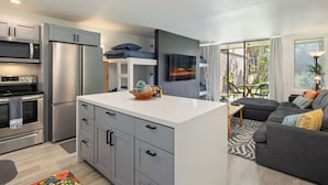 A modern kitchen with a central island, built-in appliances, and a dining area with a view. - Hanau Hideaway, 2026 Remodel, Pool, AC, Turtle Bay (Kahuku)