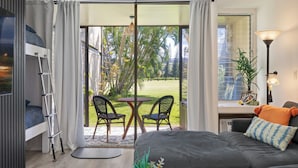 A modern bedroom with a bed, a desk, and a balcony with chairs. - Hanau Hideaway, 2026 Remodel, Pool, AC, Turtle Bay (Kahuku)