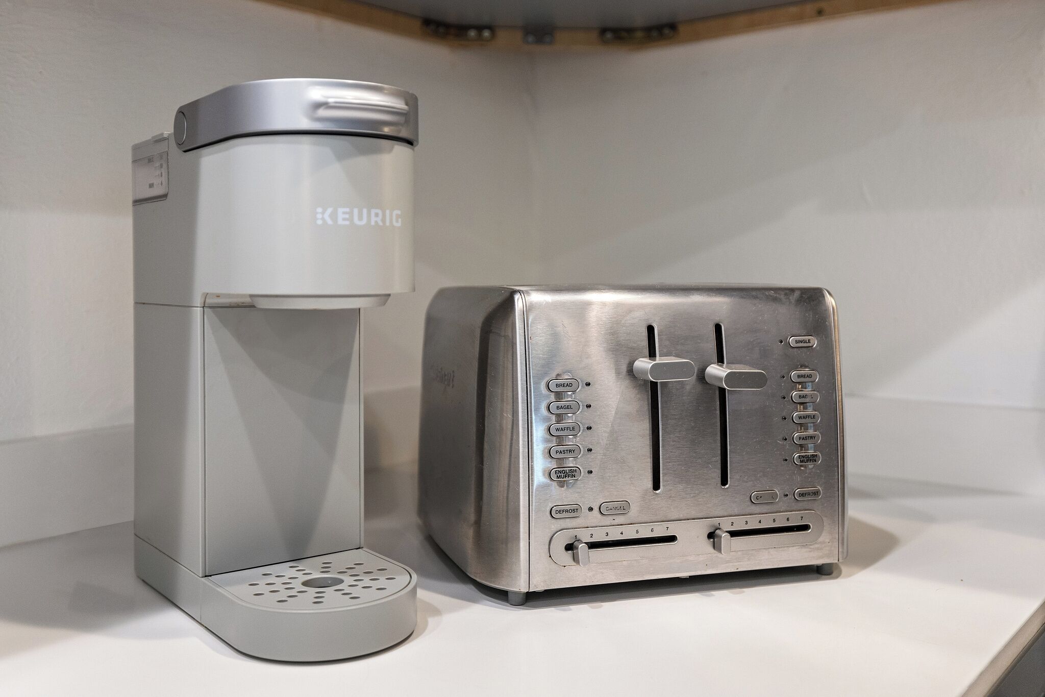 A KEURIG coffee maker and a toaster on a white countertop.