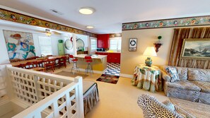 A spacious living area with a dining table, red kitchen cabinets, and a checkered floor.