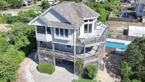A two-story house with a balcony and a small deck, surrounded by greenery and a swimming pool. - Make Way For Ducklings - Wild Duck Dunes, Ocean Views, 160 Yds to Beach, Saltwater Pool, Flex Stays (Duck)