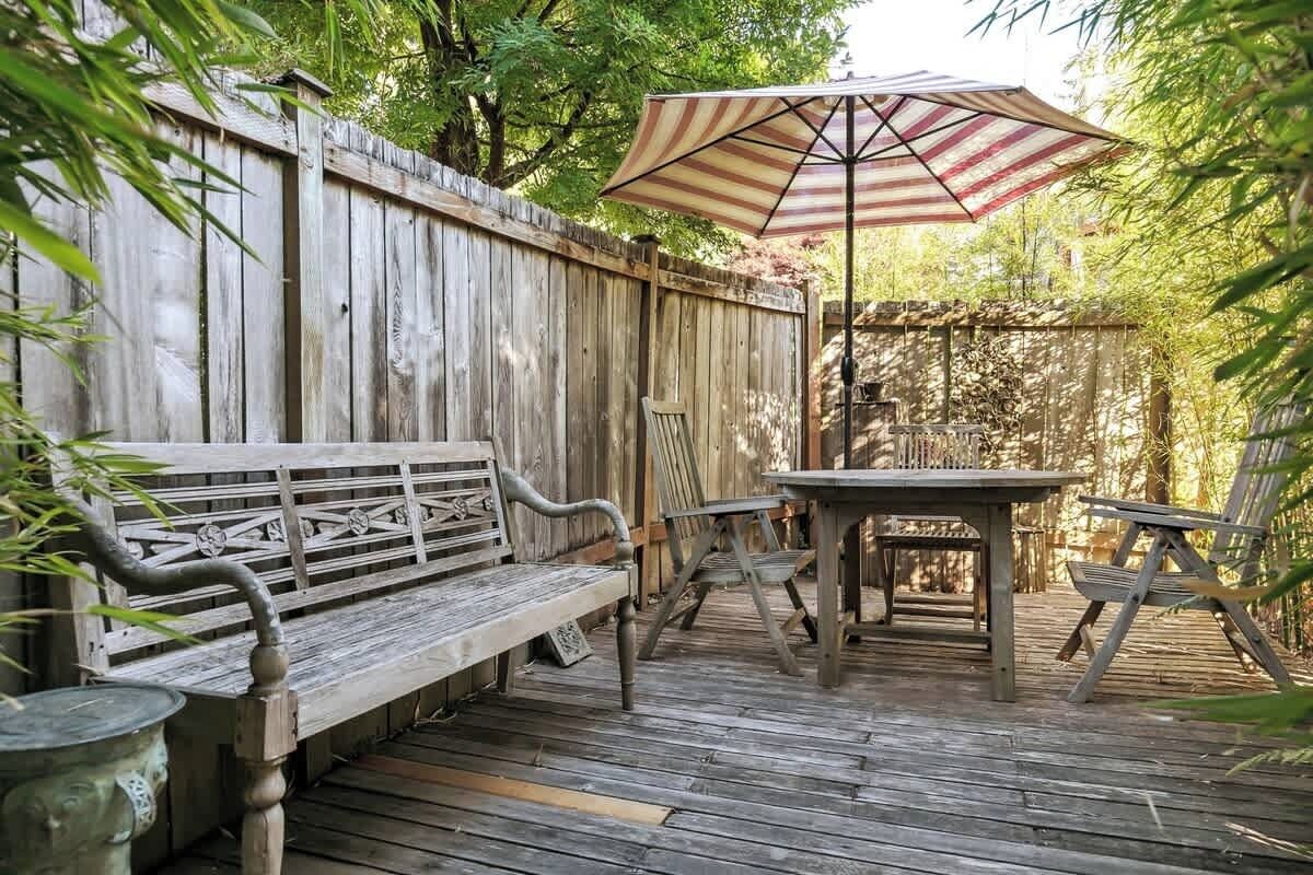 En træterrasse med bænk, bord og parasol.