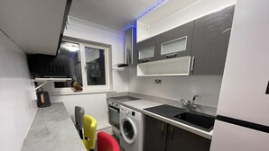 A compact kitchen with a washing machine, a sink, and a window. - Newly Refurbished Modern 2 Bedroom Flat (Trimley Saint Mary)