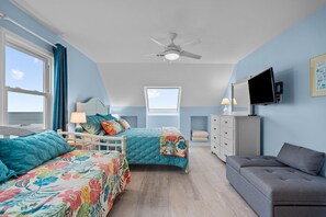 Une chambre avec deux lits, un ventilateur de plafond, une télévision et une fenêtre.