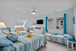 A bedroom with two beds, a ceiling fan, a TV, and a window with curtains. - Topsail's Treasure #148 - Oceanfront Home w/ Community Pool & Sound Access! (North Topsail Beach)