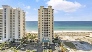 A high-rise hotel with a central courtyard, a parking lot, and a beach view. - Gulf Front Resort w/Pools. 2 chairs/umbrella included for your stay! (Navarre)