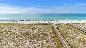 A beach with a wooden boardwalk leading to the water, sandy dunes, and a clear blue sky. - Gulf Front Resort w/Pools. 2 chairs/umbrella included for your stay! (Navarre)
