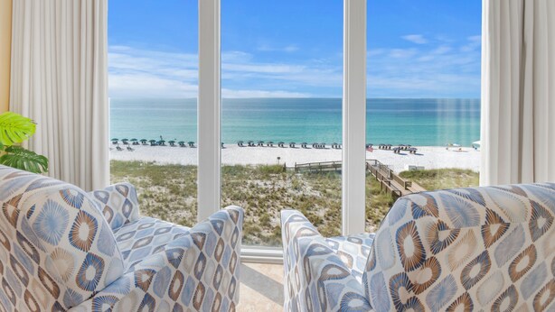 A room with a large window overlooking a beach. There are two patterned armchairs in the foreground. - Gulf Front Resort w/Pools. 2 chairs/umbrella included for your stay! (Navarre)