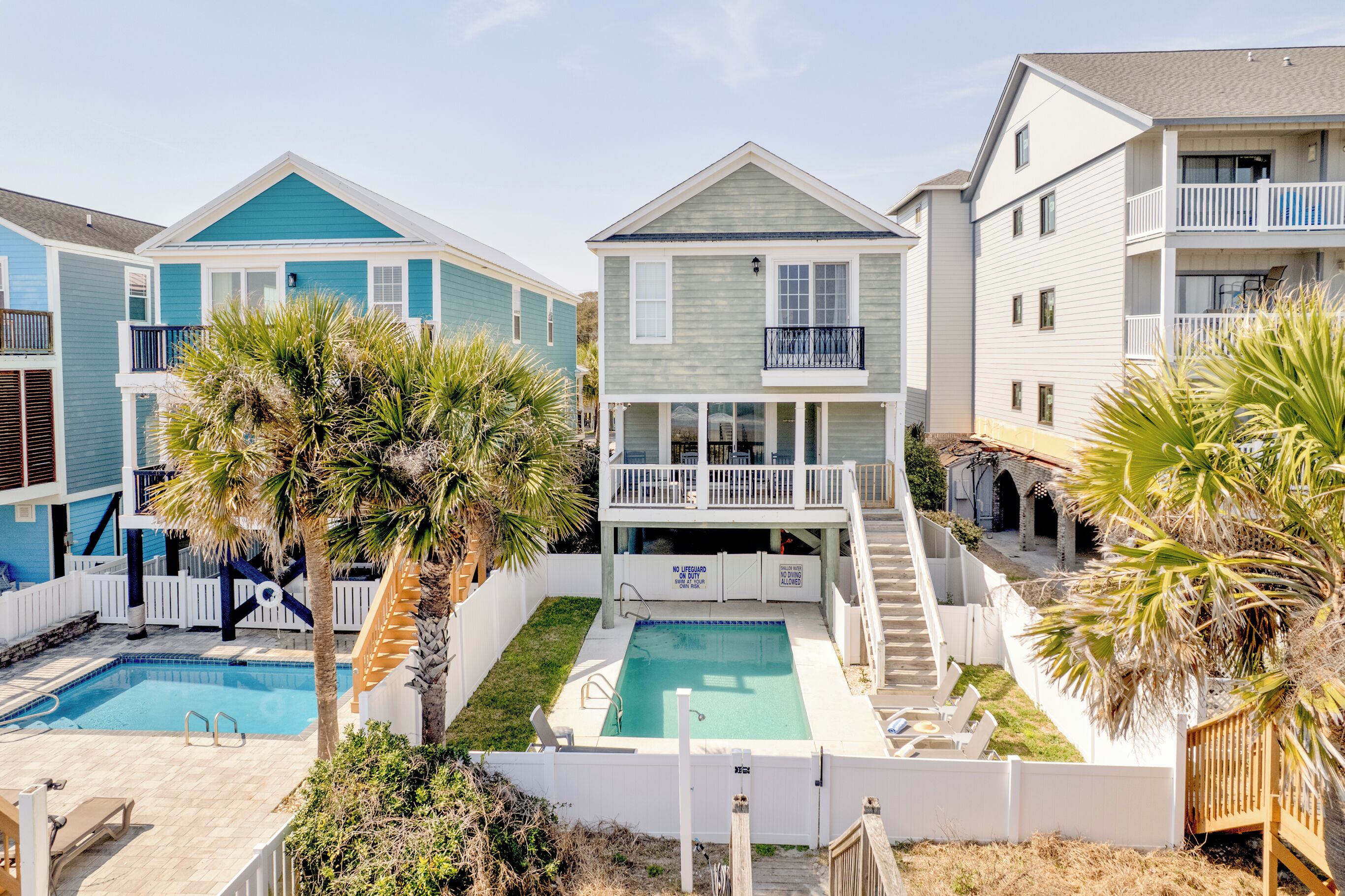 A residential building with a swimming pool, a balcony, and a staircase leading to a second floor.