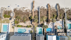 An aerial view of a resort with multiple swimming pools, a beach, and a forested area. - A Wave From It All: Oceanfront & Pool (Surfside Beach)