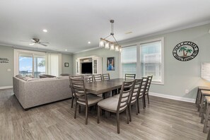 A dining area with a wooden table and chairs, a sofa, and a ceiling fan. - A Wave From It All: Oceanfront & Pool (Surfside Beach)