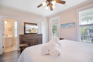 A bedroom with a bed, a ceiling fan, a television on a dresser, and a window with blinds. - A Wave From It All: Oceanfront & Pool (Surfside Beach)