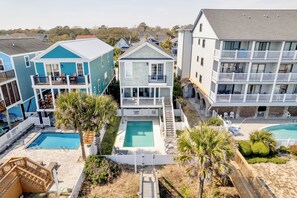 A residential building with a swimming pool, balconies, and a small deck area. - A Wave From It All: Oceanfront & Pool (Surfside Beach)