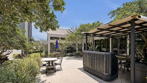 Un patio al aire libre con una mesa y sillas, un jacuzzi y una pérgola.