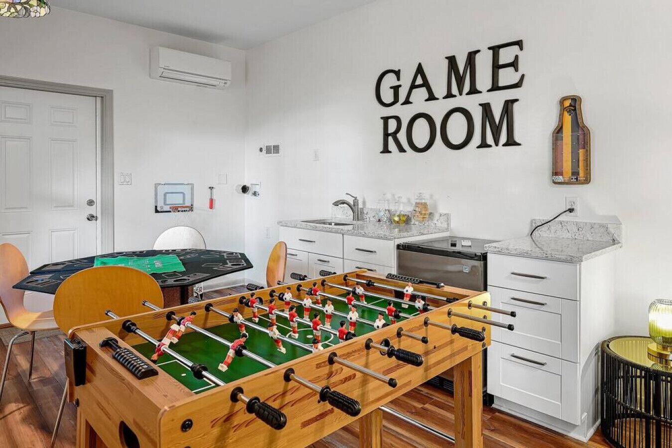 Een speelkamer met een tafelvoetbaltafel, een keukenhoek en een wandairconditioner.