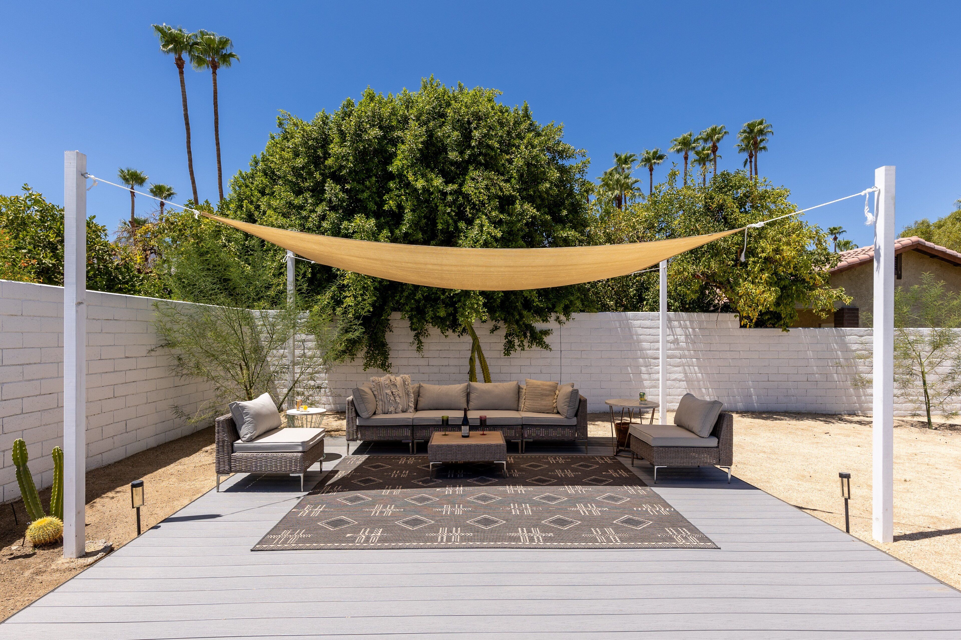 A patio with a sofa set, a patterned rug, and a canopy.