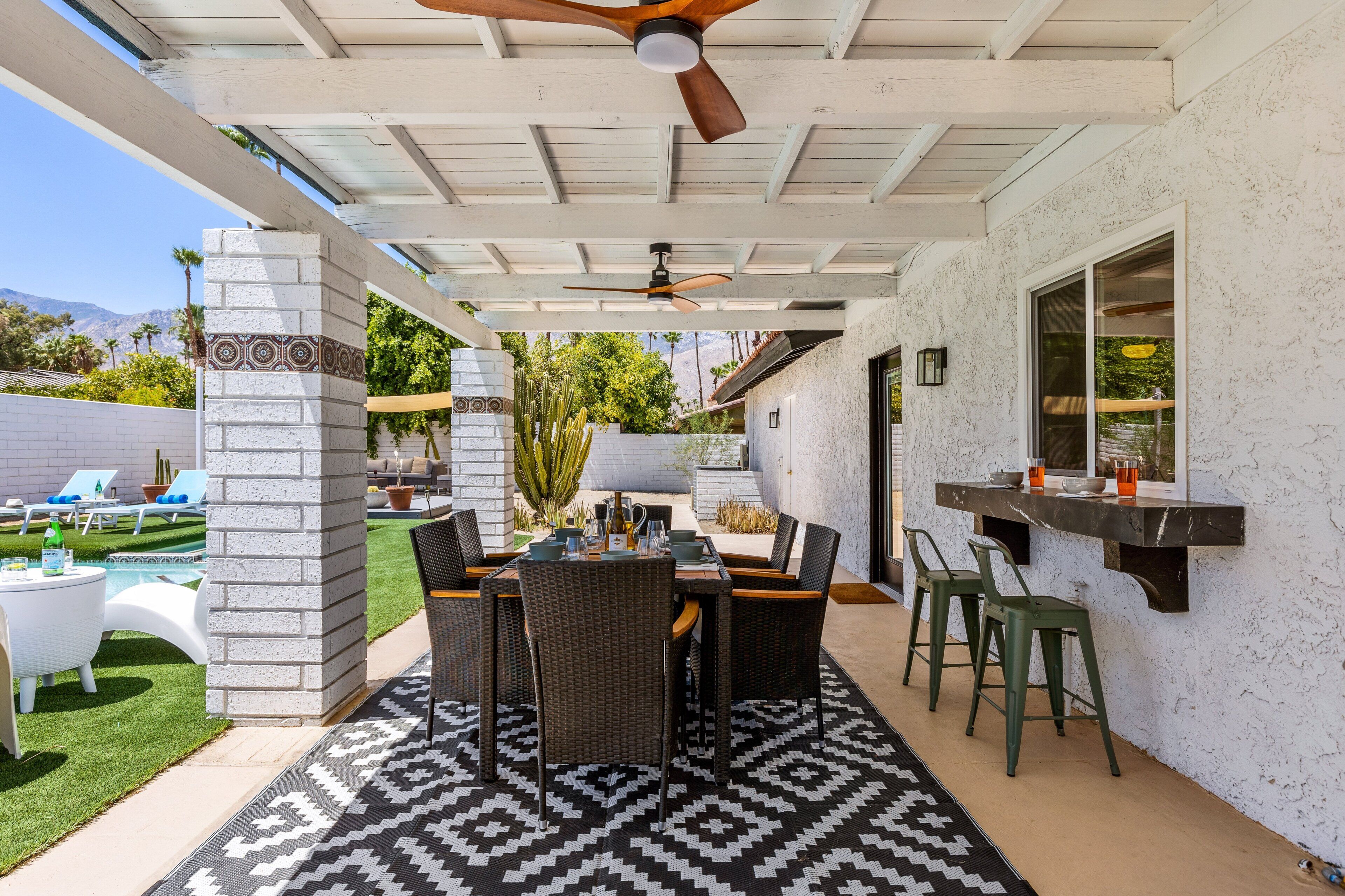 Un patio exterior con una mesa de comedor, sillas y un ventilador de techo.