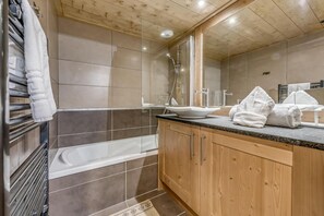 Ein modernes Badezimmer mit Dusche, Waschbecken mit Spiegel und Holzschränken.