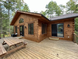Una baita di legno con veranda, ampie finestre e tavolo da picnic.