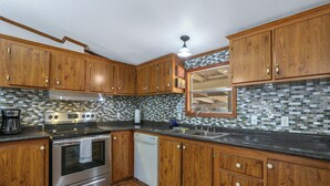 A kitchen with wooden cabinets, a stainless steel stove, and a tiled backsplash.