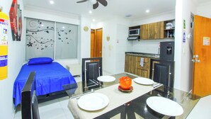 A compact hotel room with a bed, a dining table with chairs, a microwave, and a refrigerator. - 1 Bedroom Studio Apartment in Rodadero (Santa Marta)