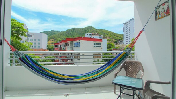 A balcony with a hammock, a small table, and two chairs.