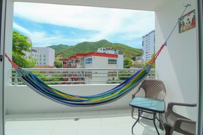 A balcony with a hammock, a small table, and two chairs. - Rodadero Studio Near the Beach (Santa Marta)