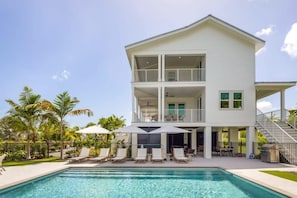 A two-story house with a pool, outdoor seating, and a covered patio area.