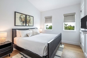 Un dormitorio moderno con una cama grande, mesitas de noche, un televisor de pantalla plana y obras de arte en la pared.