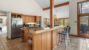 Une cuisine spacieuse dotée de meubles en bois, d’un réfrigérateur en acier inoxydable et d’un grand îlot central avec des tabourets de bar.