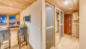 Un interior moderno con zona de comedor, techo de madera y vistas a un paisaje nevado a través de amplias ventanas.
