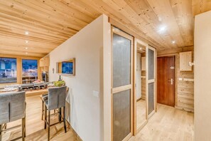 A modern interior with a dining area, wooden ceiling, and a view of a snowy landscape through large windows. - 20m from resort center, 6th floor, view mountain, balcony, tv, ski locker, 55m², Tignes (Tignes)