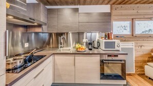 Una cocina moderna con electrodomésticos de acero inoxidable, armarios de madera y vistas a un paisaje nevado a través de amplios ventanales.