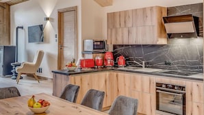 A modern kitchen with wooden cabinets, a black marble backsplash, and stainless steel appliances. - 1st floor, swimming pool, sauna, balcony, fireplace or stove, parking, tv, ski locker, 83m² (Champagny-en-Vanoise)