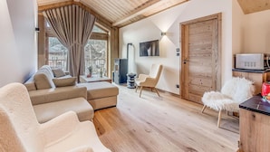 A cozy living room with a sofa, armchairs, a TV, and a fireplace. - 1st floor, swimming pool, sauna, balcony, fireplace or stove, parking, tv, ski locker, 83m² (Champagny-en-Vanoise)