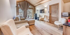 A cozy living room with a sofa, armchairs, a TV, and a fireplace.