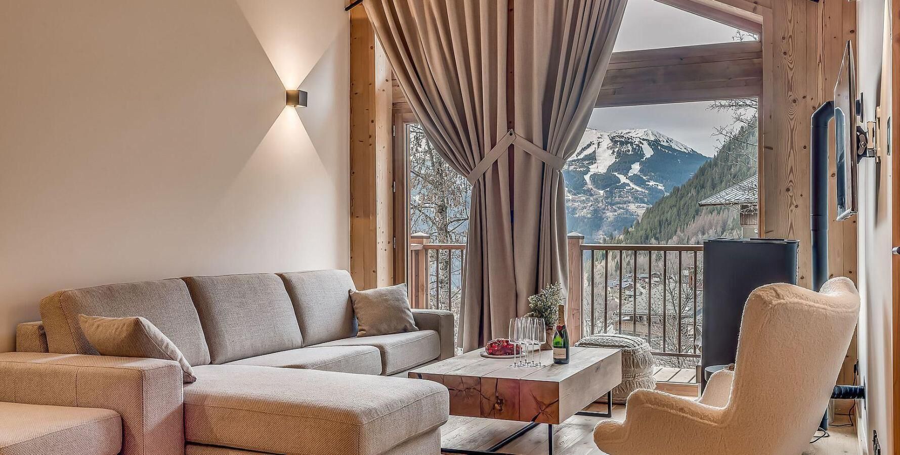 Un salón acogedor con un sofá, un sillón y una mesita de centro. Una ventana ofrece vistas a montañas nevadas.