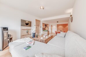 A modern, well-lit room with a sofa, a dining table, and a kitchen area.
