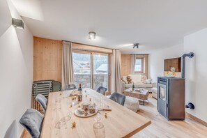 Een moderne woonkamer met een houten eettafel gedekt voor een maaltijd, een bank en een open haard.