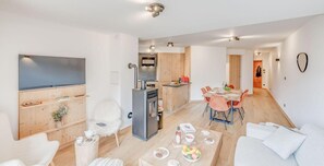 Een moderne woonkamer met een open haard, een eethoek met een houten tafel en stoelen, en een keuken met een fornuis.