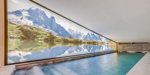 Een modern binnenzwembad met een panoramisch berglandschap op de muur.