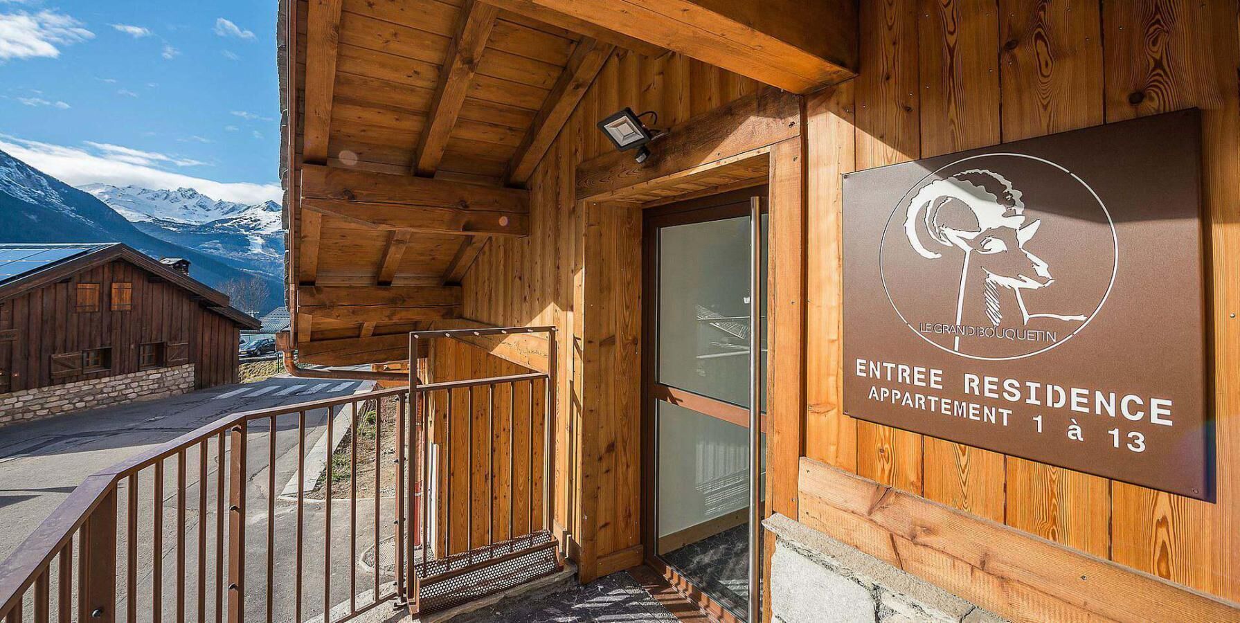 A wooden building with a sign indicating 'ENTREE RESIDENCE APPARTMENT 1 à 13'.