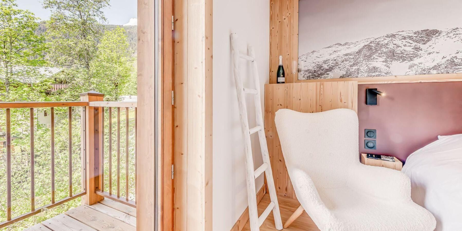 Una habitación de madera con una silla blanca, una escalera y una cama.