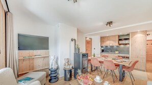A modern living room with a flat-screen TV, a fireplace, and a dining area with pink chairs and a table set for tea. - Ground floor, swimming pool, sauna, balcony, fireplace or stove, parking, tv, ski locker, 59m² (Champagny-en-Vanoise)