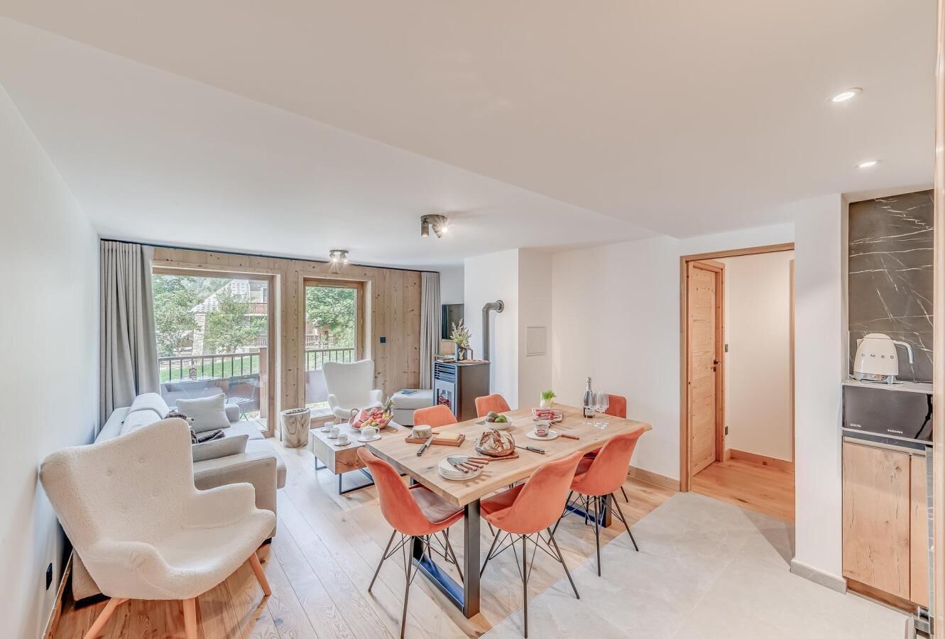 A modern living room with a dining area, large windows, and a kitchen.