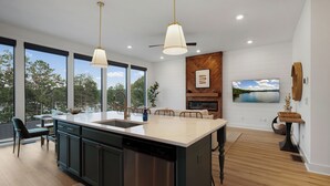 A modern kitchen with a large island, wooden flooring, and a dining area with a view of the outdoors. - A Stoney Marina - Lake Arrowhead (Waleska)