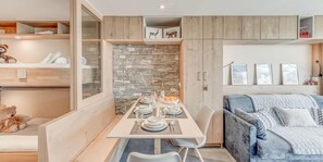 A modern living space with a dining area, a sofa, and a teddy bear.