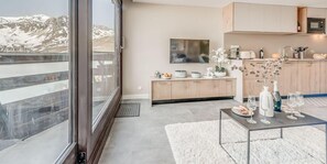 A modern kitchen with a large window, wooden cabinets, and a dining area with a table set for four.