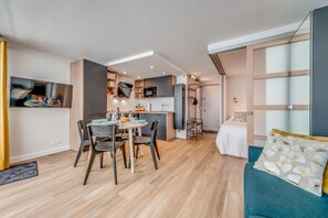 A modern interior with a dining area, kitchenette, and a bed with a blue accent wall.
