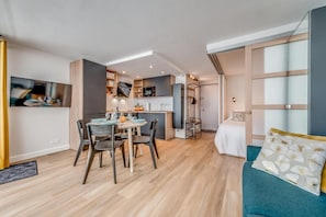 A modern interior with a dining area, kitchenette, and a bed with a blue accent wall.